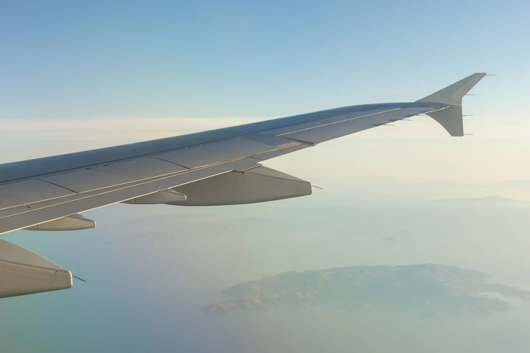 An aircraft wing above an island seen from the air